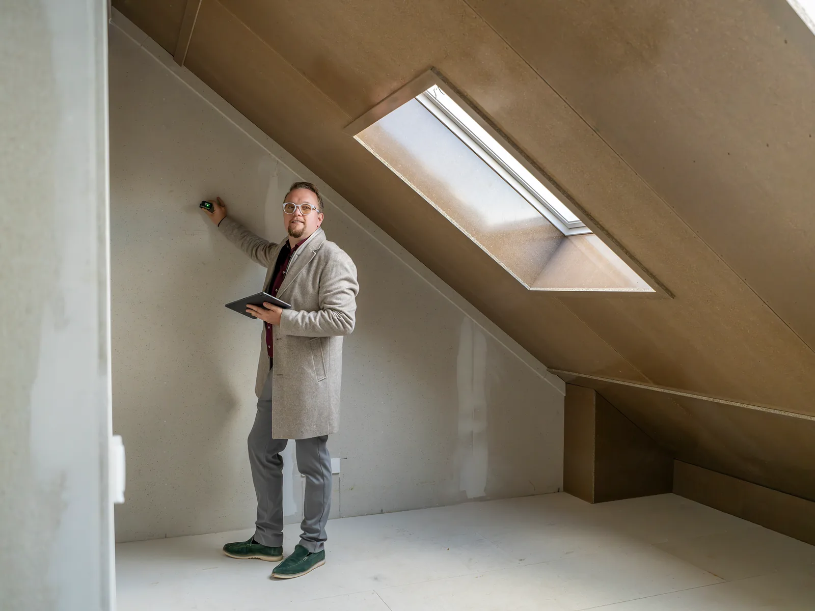Mark Korbee meet een zolder met een dakraam in, met een laserafstandsmeter en een tablet